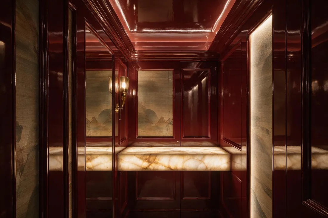 Jewel box maximalist powder room with backlit onyx counter and concealed door at night