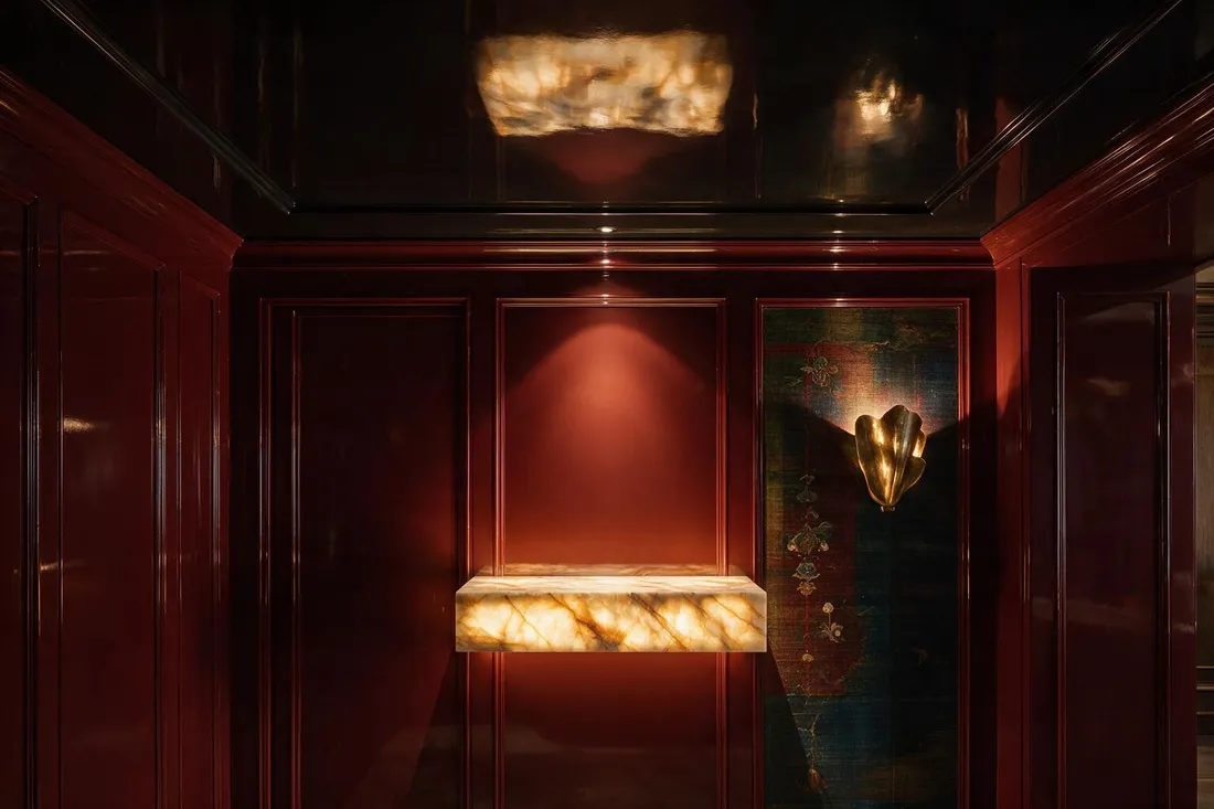 Jewel box maximalist powder room with a backlit onyx counter and concealed door